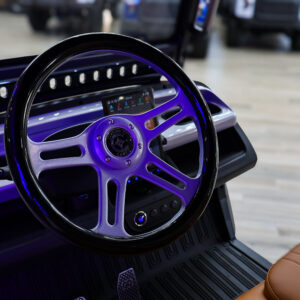 Steering wheel and dashboard display of the Conquest S20 electric golf cart inside Galaxy Golf Cars showroom