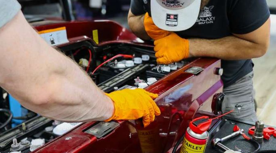 Galaxy Golf Cars technicians performing golf cart battery maintenance and electrical system inspection on an electric golf cart